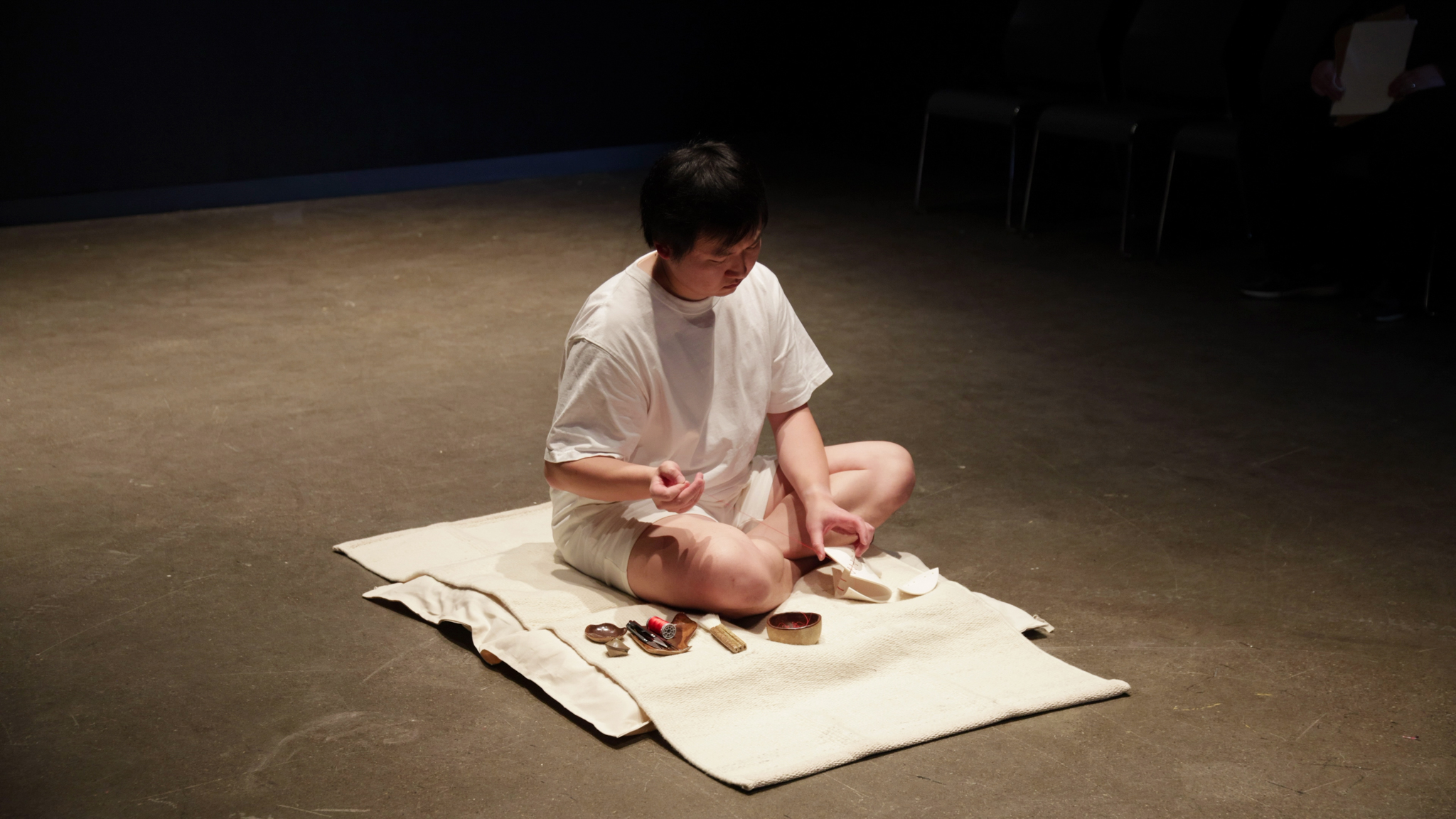 Artist sitting on floor with tools mending a ceramic art piece.